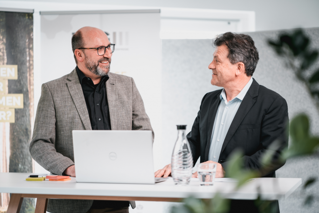 TCG_Mitarbeitende_beim_Gespräch_vor_Computer