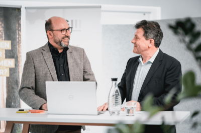 TCG_Mitarbeitende_beim_Gespräch_vor_Computer